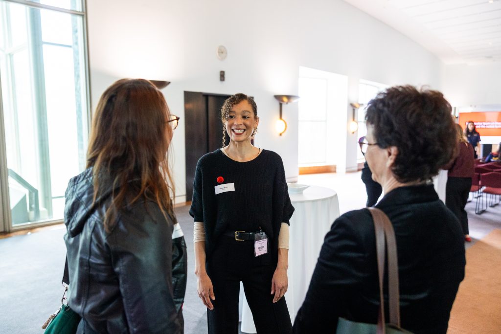 Three women having a conversation together and smiling.