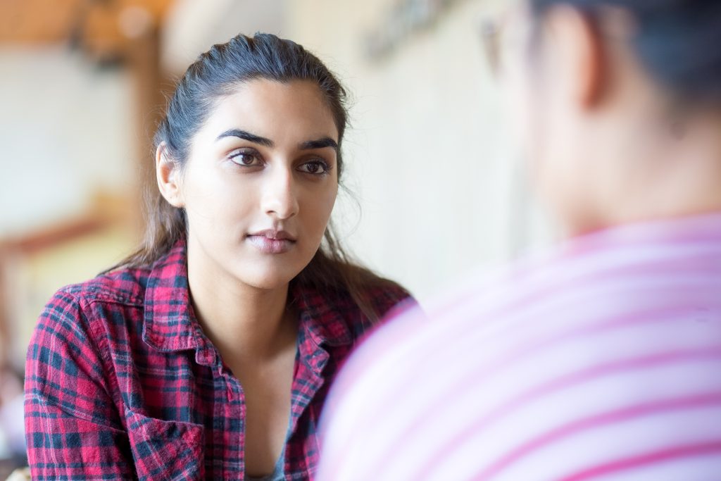 A young woman listening to her friend while in conversation together.