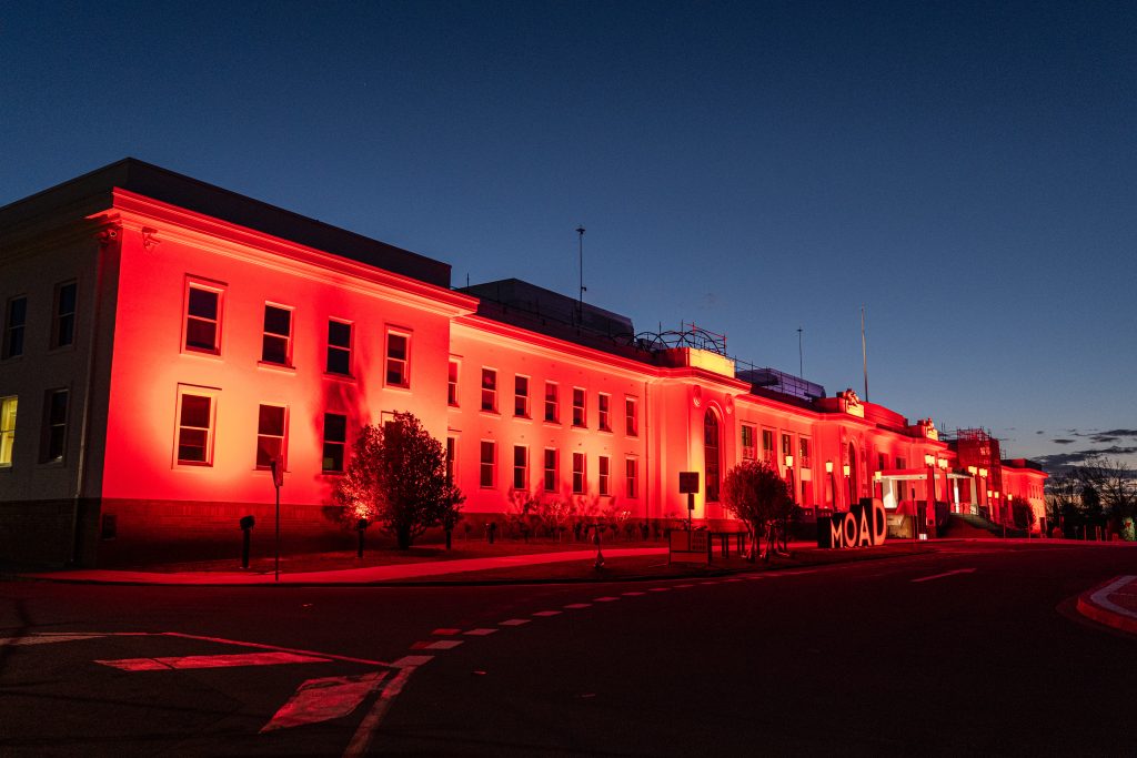 A historical old building lit up red at night time.